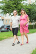 a happy young pregnant woman with her husband walking in a park
