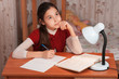 thoughtful girl doing homework at the table