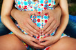 Man embraces his pregnant wife and shows heart by hands