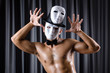 Muscular actor with mask against curtain
