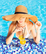 Foto: Pretty blond woman enjoying cocktail in a swimming pool Pretty blond woman enjoying cocktail in a swimming pool