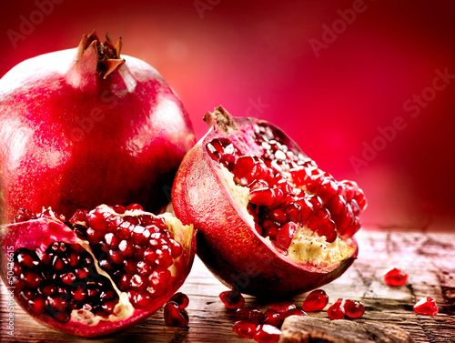 Photo: Pomegranates over Red Background. Organic Bio fruits Pomegranates over Red Background. Organic Bio fruits