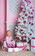 The girl at the Christmas fir-tree with gifts