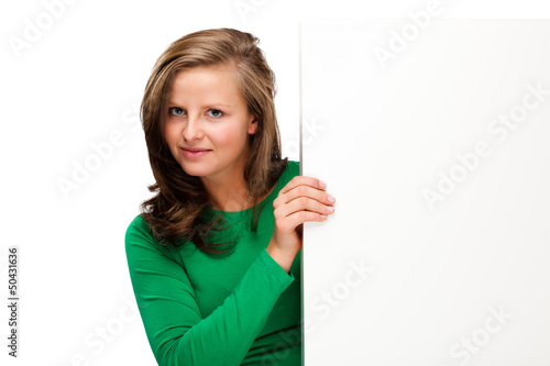 Photo: Young attractive girl behind empty board on white background Young attractive girl behind empty board on white background