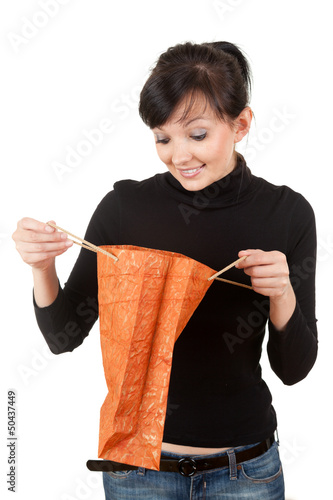 Photo: young woman with curiosity looking to gift bag young woman with curiosity looking to gift bag