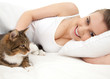 beautiful girl lyng in white bedding with cat