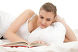 Photo: student woman reading book in white bedding student woman reading book in white bedding