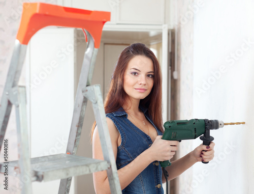 Photo: Beautiful woman in overalls with drill Beautiful woman in overalls with drill