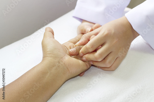 Photo: Physical therapist checks range of motion patient's hand before Physical therapist checks range of motion patient's hand before