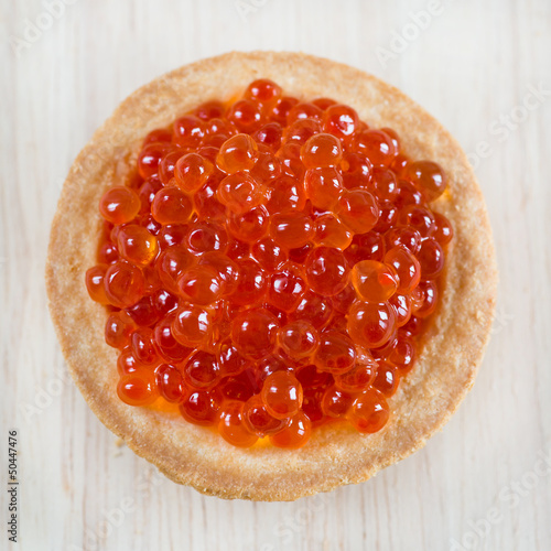 Photo: Tartlet with red caviar on light wooden background Tartlet with red caviar on light wooden background