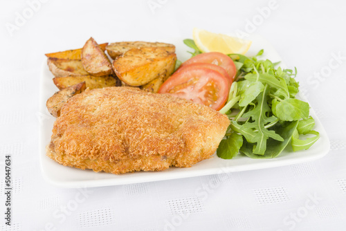Photo: Wiener Schnitzel - Breaded fried veal, potato wedges and salad. Wiener Schnitzel - Breaded fried veal, potato wedges and salad.