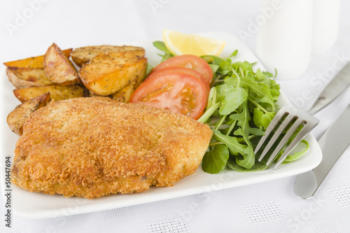 Photo: Wiener Schnitzel - Breaded fried veal, potato wedges and salad. Wiener Schnitzel - Breaded fried veal, potato wedges and salad.