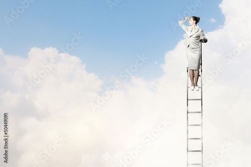 Photo: Businesswoman standing on ladder Businesswoman standing on ladder