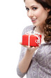 Enigmatic young woman hands a gift wrapped in red paper