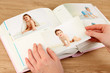 Photos in hands and photo album on wooden table