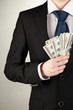 Business man hiding money in pocket on grey background