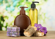 Liquid and hand-made soaps on wooden table, on green background