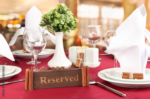 Photo: Reserved sign on restaurant table with empty dishes and glasses Reserved sign on restaurant table with empty dishes and glasses