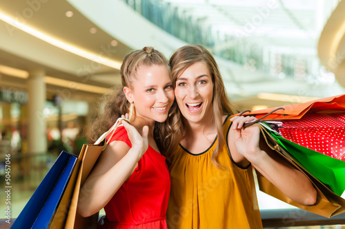 Photo: Two women shopping with bags in mall Two women shopping with bags in mall