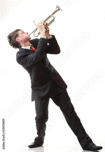 Photo: Portrait of a young man playing his Trumpet plays isolated Portrait of a young man playing his Trumpet plays isolated