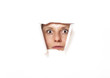 Foto: Young woman looking through torn paper hole Young woman looking through torn paper hole