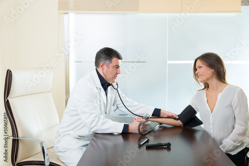 Photo: Doctor man checking blood pressure cuff on woman patient Doctor man checking blood pressure cuff on woman patient