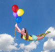 Young pretty girl fly on colorful balloons in the blue sky
