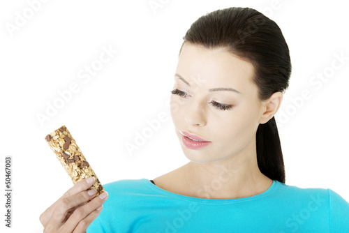 Photo: Young woman eating Cereal candy bar Young woman eating Cereal candy bar