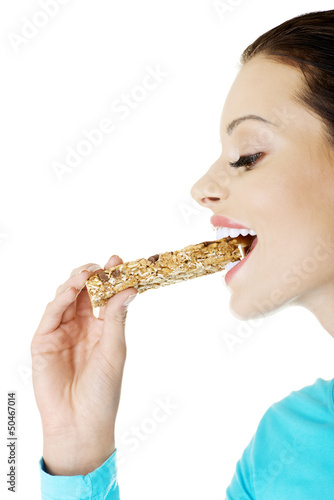 Photo: Young woman eating Cereal candy bar Young woman eating Cereal candy bar