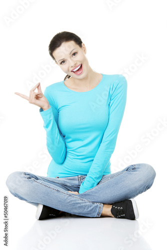 Photo: Happy , excited young woman pointing on copy space Happy , excited young woman pointing on copy space