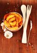 Appetizing village potatoes in bowl on wooden table close-up