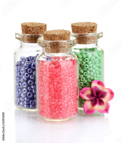 Photo: Little bottles full with colorful beads isolated on white Little bottles full with colorful beads isolated on white