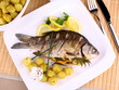 Grilled fish served with potatoes, lemon and sauce