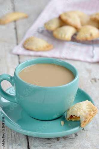 Photo: Cup of coffee with milk and apple pies on wooden background Cup of coffee with milk and apple pies on wooden background