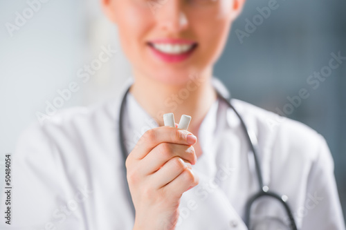 Photo: Young female dentist doctor holding chewing gum and smiling. Ora Young female dentist doctor holding chewing gum and smiling. Ora