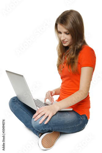Photo: Young woman sitting on the floor while using her laptop Young woman sitting on the floor while using her laptop