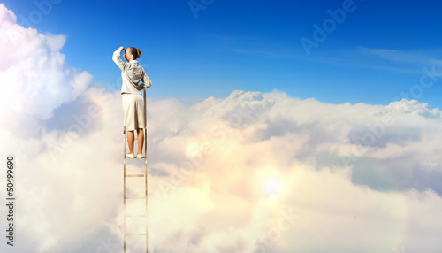 Photo: Businesswoman standing on ladder Businesswoman standing on ladder