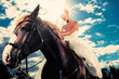 Bride in wedding dress riding a horse, backlit