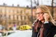 Foto: Young woman in front of taxi with phone Young woman in front of taxi with phone