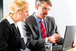 Businesspeople looking at laptop in consultation