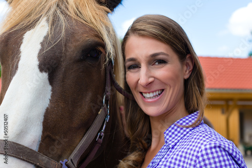 Photo: Young woman in the stable with horse in sunshine Young woman in the stable with horse in sunshine