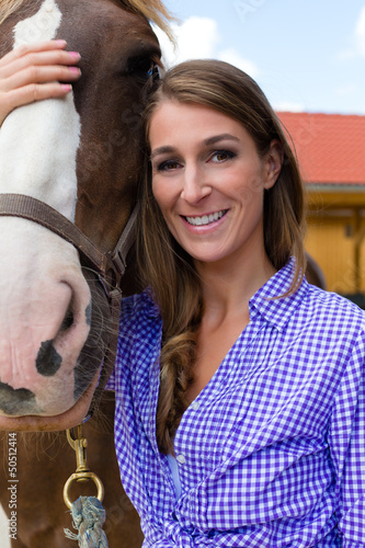 Photo: Young woman in the stable with horse in sunshine Young woman in the stable with horse in sunshine