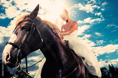 Photo: Bride in wedding dress riding a horse, backlit Bride in wedding dress riding a horse, backlit