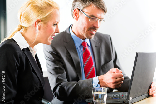 Photo: Businesspeople looking at laptop in consultation Businesspeople looking at laptop in consultation