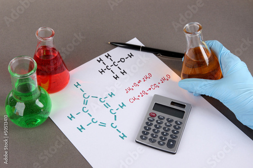 Photo: Test tubes with colorful liquids and formulas on grey Test tubes with colorful liquids and formulas on grey