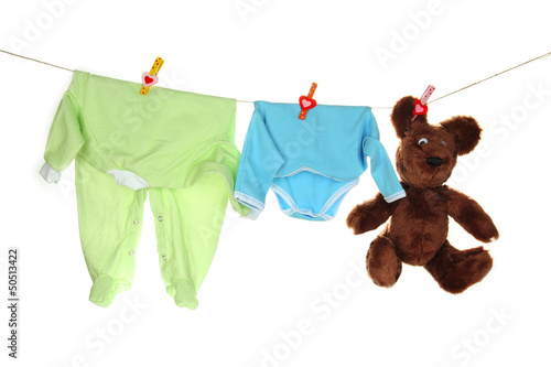 Photo: Baby clothes hanging on clothesline, isolated on white Baby clothes hanging on clothesline, isolated on white
