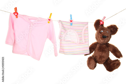 Photo: Baby clothes hanging on clothesline, isolated on white Baby clothes hanging on clothesline, isolated on white