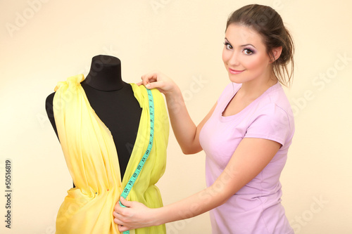 Photo: Beautiful young dressmaker in workroom Beautiful young dressmaker in workroom