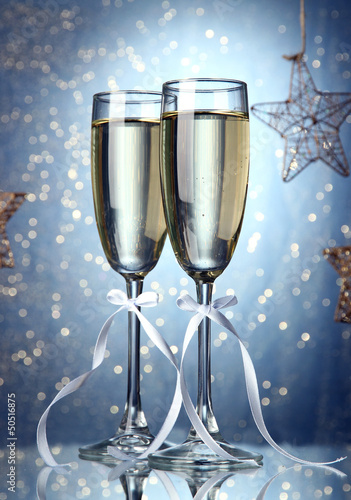 Photo: Two glasses of champagne on bright background with lights Two glasses of champagne on bright background with lights