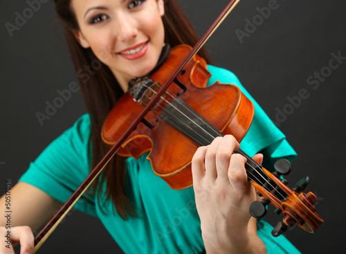 Photo: Beautiful young girl with violin on grey background Beautiful young girl with violin on grey background